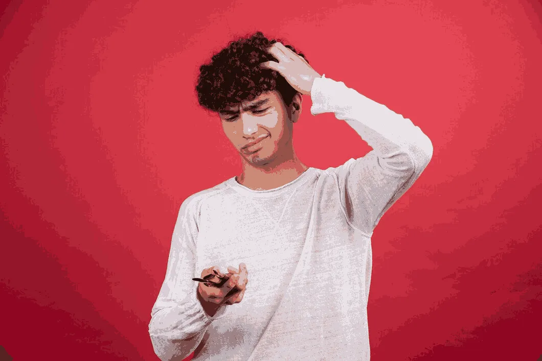 Young man noticing early genetic hair loss and thinning hair in his twenties