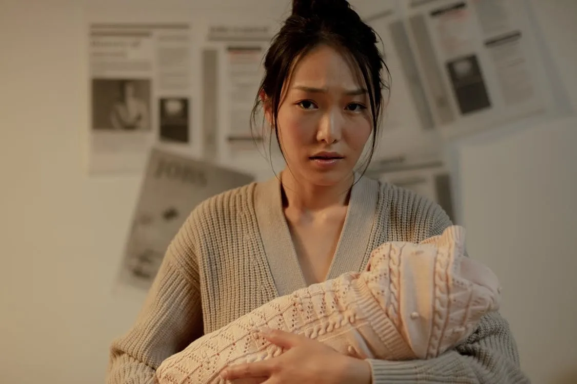 New mother experiencing postpartum hair loss after pregnancy while holding baby.